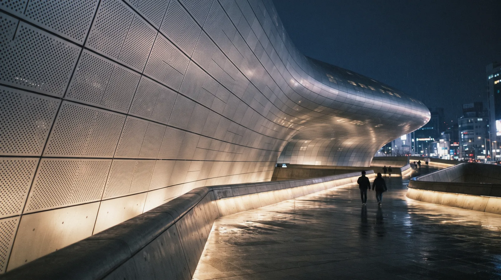 The seamless curved aluminium exterior of Dongdaemun Design Plaza at night with people on the plaza, Seoul, South Korea